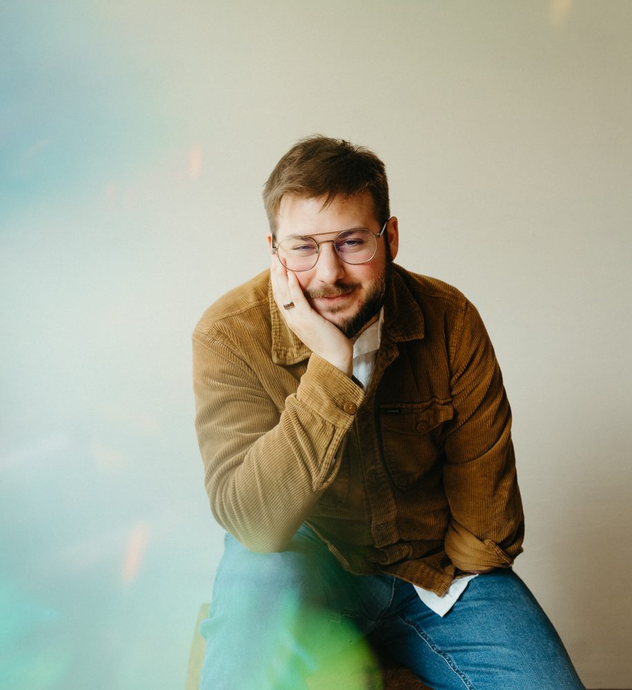 Christian smiling with his chin in his hand, corduroy jacket, soft light leak