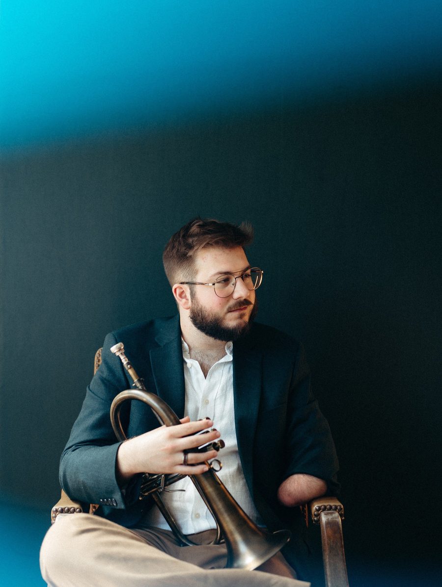 Christian Dyble seated with a flugelhorn under a teal glow